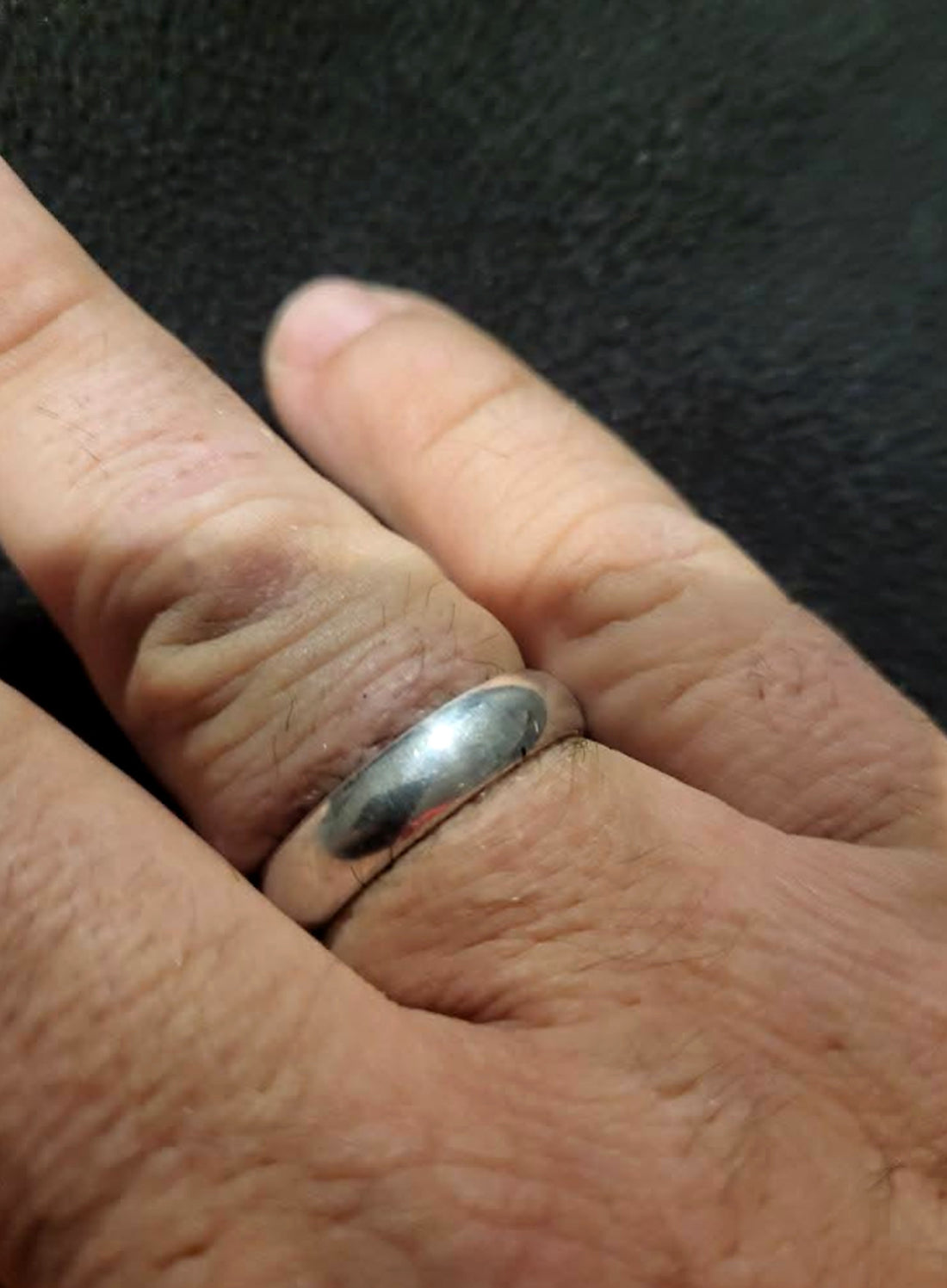 A handmade silver wedding band worn on a finger